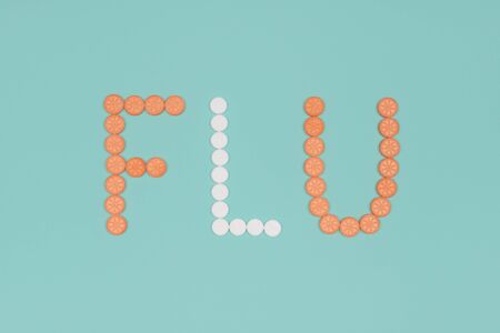 Medical background with pills. Flu season or influenza concept. The word flu made from the assorted pills on pink background. Pharmacy theme, health care, drug prescription for medication treatmentの写真素材
