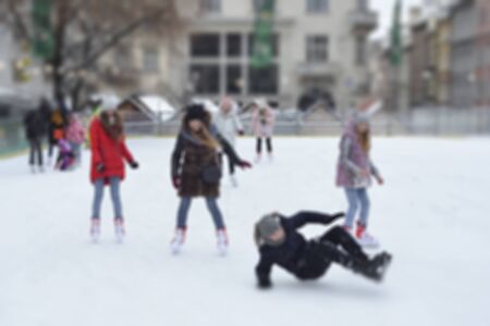 Happy people outdoor ice skating at rink. Winter activities. Defocused outdoor ice skating rink with skating people in winter holiday season.の写真素材