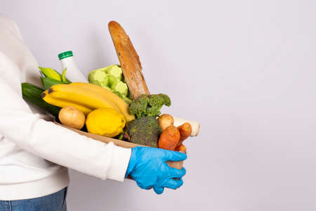 Safe food delivery or donation concept. Food delivery or shopping during quarantine. Girl in...