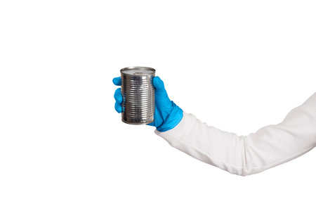Female hand in blue disposable gloves holds tin with canned food or preserves. Kitchen and food...