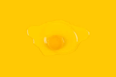 Broken raw egg isolated on yellow background.の写真素材