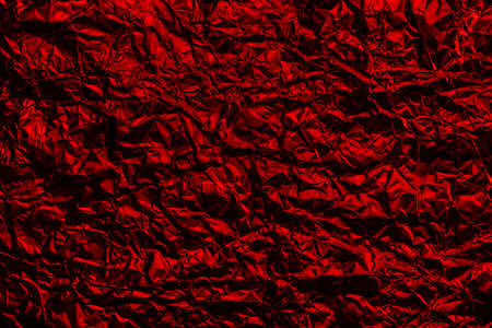 Red foil background with shiny crumpled surface for texture background. Iridescent surface wrinkled foil.の写真素材