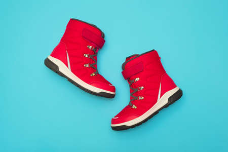 Kids or teenage pink winter boots isolated on blue background. Winter boots for girls.