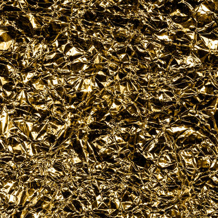 Golden foil background with shiny crumpled surface for texture background. Iridescent surface wrinkled foil.の写真素材