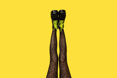 New gray female boots with bright yellow laces on straight, long slender woman legs in gray tiger...