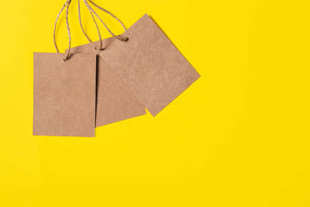 Three Craft brown paper tags isolated on bright yellow background. Sale or price banner with copy space in minimal style.の写真素材