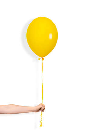 Hand hold yellow balloon. Party or present concept. Yellow Balloon and hand isolated on white backgroundの写真素材