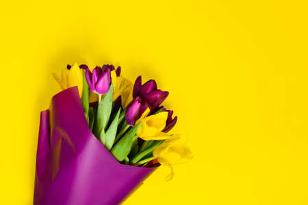 Bouquet of yellow and purple tulips on yellow background. Greeting card template with copy space. Concept of holiday on March 8, Women's Day, Valentine's Day, mother's day. Spring banner. Top view.の写真素材