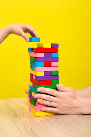 Hands close up playing a round of tower with wooden blocks. Planning, risk and strategy in business...