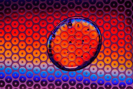 Transparent gel drop on neon blue and pink background. Top view. Virus protection or cosmetics concept. Serum texture close up.の写真素材