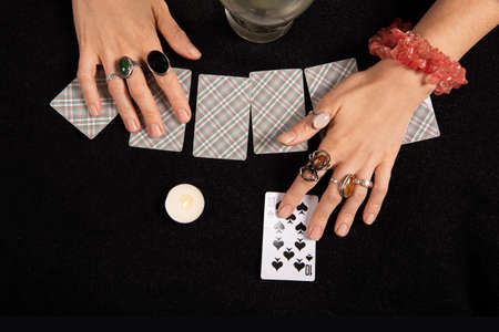 Fortune teller or witch hands, cards, candles and a glowing magic ball. Halloween, magic and tricks...
