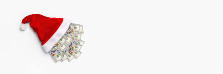 New year or Christmas gift concept. Money inside Santa hat. Christmas hat full of 100 dollar bill...