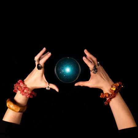 Fortune teller or witch hands and a glowing magic ball isolated on dark background. Halloween, magic...