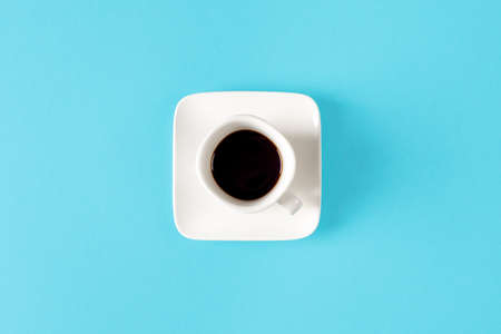 White cup of coffee isolated on a blue background. minimal styleの写真素材