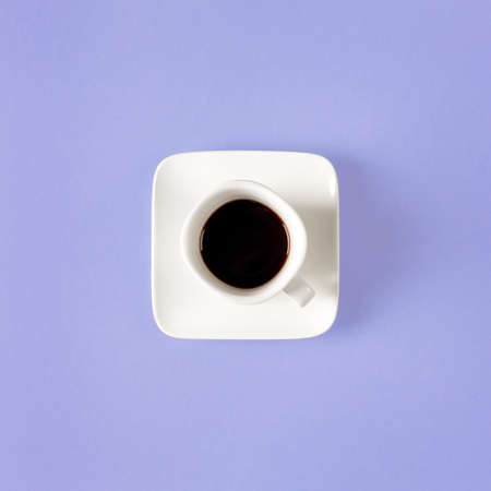 White cup of coffee isolated on a purple background. minimal style. Square composition.の写真素材
