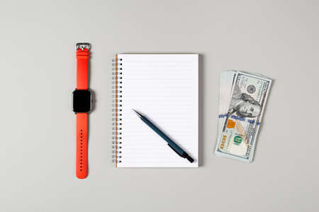 Notepad, pen, stack of money and a cup of black coffee isolated on gray background. Notepad with copy space. Office, business, financial growth concept.の写真素材