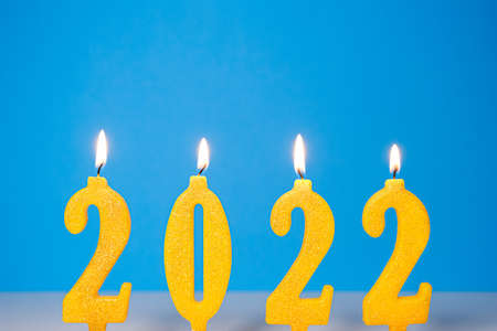 Holiday background of burning yellow candles 2022 Happy New Year concept Burning yellow and golden...