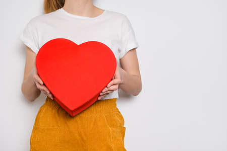 Woman holding a big red box in shape of a heart. Trendy video banner for Valentines Day, International Womens Day or mothers day.の写真素材