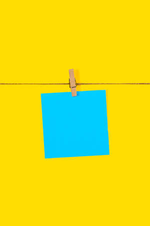 Blue Note papers and decorative pin or clip isolated on yellow background. Office mock up. Top view, flat lay. Colorful office note or sticker papers. High quality photoの写真素材