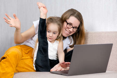 Little girl demonstrates to her family on a laptop her skills in dance and gymnastics. online...