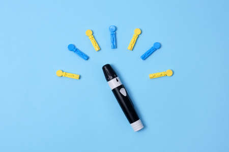 Diabetes concept on blue background. An abstract clock made of interchangeable needles and a lancet for blood sugar testing.の写真素材