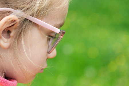 Girl child holds and blows on a dandelion. Happy childhood concept. Playing outdoors. Sad or concentrated Child looking ahead.の写真素材