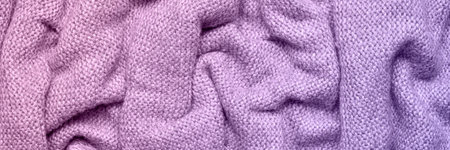 A soft and textured gradient lilac and purple knitted fabric with gentle waves and folds, creating a cozy and warm appearance. Ideal for textile backgrounds, fashion, or home decor themes.の写真素材