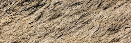 A close up of a rough, cracked rock surface with earthy brown and beige tones. The natural texture and weathered details make it ideal for backgrounds, geology themes, and organic material references.の写真素材