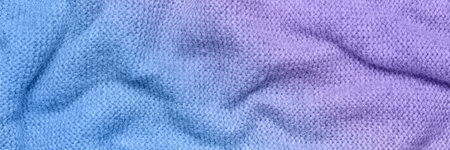 A soft and textured gradient blue and purple knitted fabric with gentle waves and folds, creating a cozy and warm appearance. Ideal for textile backgrounds, fashion, or home decor themes.の写真素材