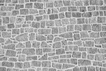 Black and white close-up of an irregular stone wall. The rough texture and natural patterns create a rustic and historical appearance. Ideal for backgrounds, textures, and architectural themes.の写真素材