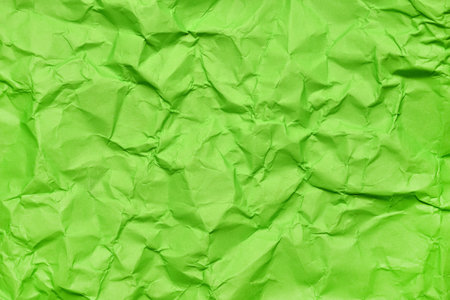 A textured green crumpled paper background with natural creases and folds. Ideal for design projects, digital graphics, or creative presentations requiring a vibrant, tactile surface elementの写真素材