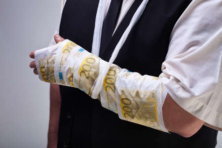 Cost of healtcare concept with euro banknotes bandage on male hand - closeupの写真素材