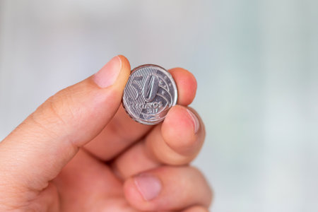 Brazilian 50 cents coin in the palm of a person. Hand holding at 50 real cents coin. Real is the...