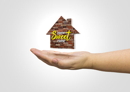 3D illustration of a hand holding an icon of a house. Home sweet home on isolated white backgroundの写真素材