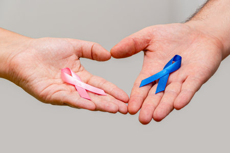 Two hands holding two Pink and Blue ribbons for the Pink October and Blue November campaigns to support life and raise awareness about cancer. Man's hand and woman's handの写真素材