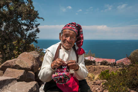 TAQUILE ISLAND, PUNO, PERU - OCTOBER 13, 2016: Close up portrait of old peruvian man knitting hat in the traditional way on Lake Titicaca to the island of Taquile in Peru.のeditorial素材