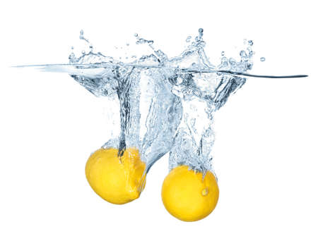 Two ripe lemons falling into the water with splashes isolated on white. Refreshing background, healthy food concept and idea.の写真素材
