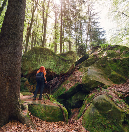 Red-haired young woman with backpack enjoying her trail in the green spring forest. Active life concept.の写真素材