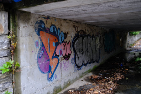 Graffiti on the side of an old concrete bridge over the riverの写真素材