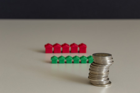 Stacked coins with miniature house. Finance items for real estate agency.の写真素材