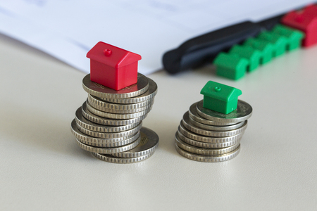 Stacked coins with miniature house. Finance items for real estate agency.の写真素材