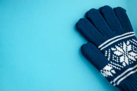 Pair of gloves isolated on the blue background. Dark blue mittens close-up with copy space.の写真素材