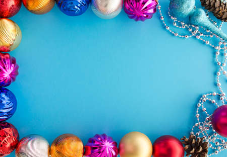 Decorative frame with colorful balls, festoon, cones and empty space for text. Merry Christmas theme. Spruce and fir tree decorations. Happy New Year. Winter holidays and celebration.の写真素材
