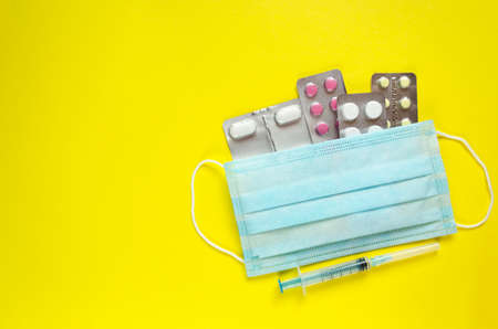 Pills, syringe, medical mask with copy space. Coronavirus disease treatment. Stop Covid-19. Pharmacy business. Medicines flat lay. Hygiene, health care and protection theme.の写真素材