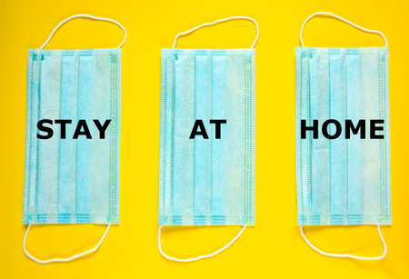 Stay at home. Medical mask on yellow background top view. Surgical masks flat lay. Coronavirus...
