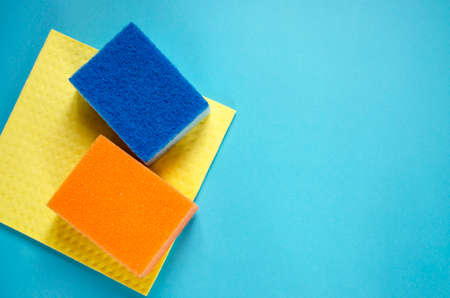 Sponges on blue background, top view. Cleaning service. Wash clothes flat lay. Advertising for...