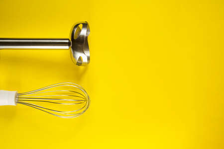 Chopper and whisk nozzles for blender device. Kitchen accessories on yellow background with copy space. Cooking and baking theme.の写真素材