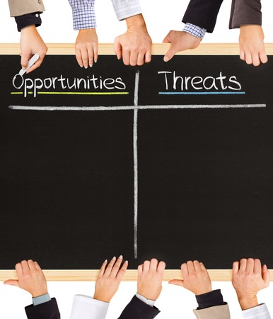 Photo of business hands holding blackboard and writing Opportunities and Threatsの写真素材