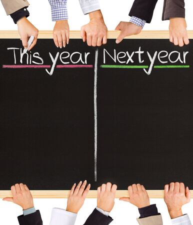 Photo of business hands holding blackboard and writing This and Next yearの写真素材