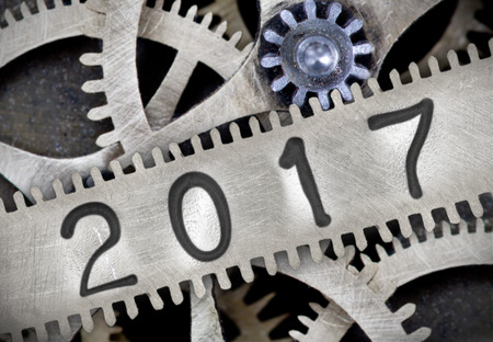 Macro photo of tooth wheel mechanism with number 2017 imprinted on clean metal surface; New Year...